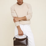 Man holding a Gold Chocolate Hobo Shoulder Handbag  against a plain background