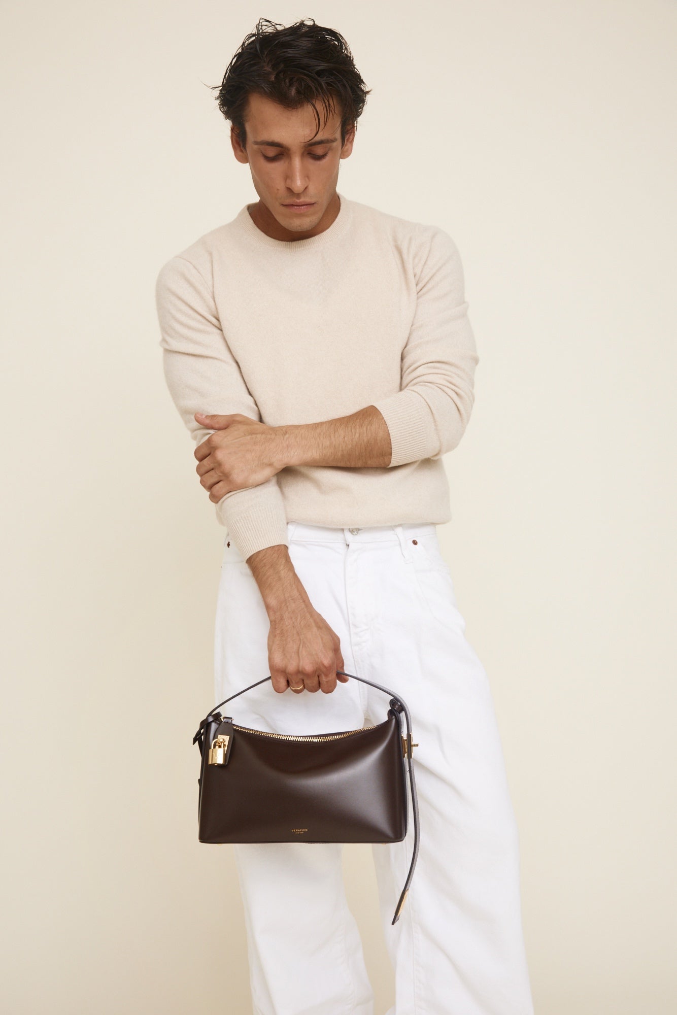 Man holding a Gold Chocolate Hobo Shoulder Handbag  against a plain background