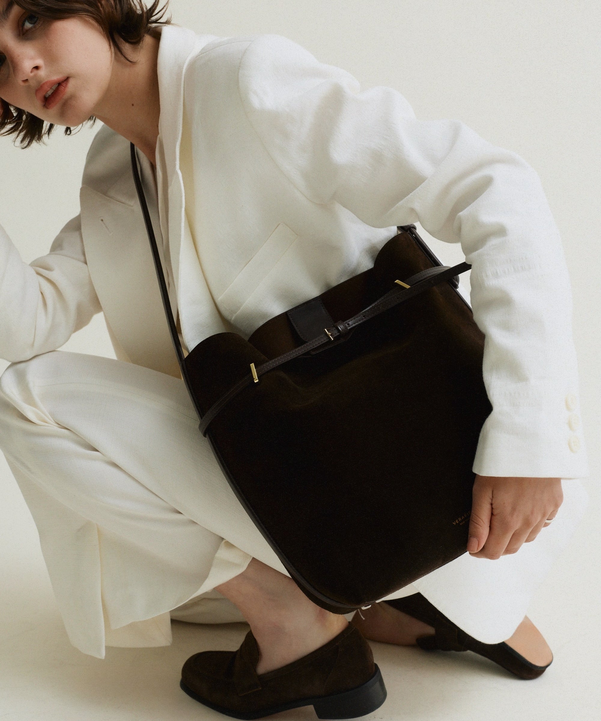 Person wearing a white outfit with a Espresso Suede Belted Tote Shoulder Bag on a plain background