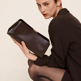 Woman holding a Chocolate Éclair Clutch Shoulder Handbag against a plain background