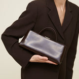 Woman holding a Chocolate Éclair Clutch Shoulder handbag against a neutral background
