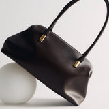 Chocolate Medium Club Shoulder Handbag with gold accents on a light gray background