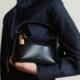Person holding a Mini Gold Black Hobo Shoulder Handbag with a gold lock, wearing a dark coat.