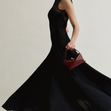 Woman in a black dress holding a r Maroon Python Café Mini Bag: Crossbody Handbag against a neutral background