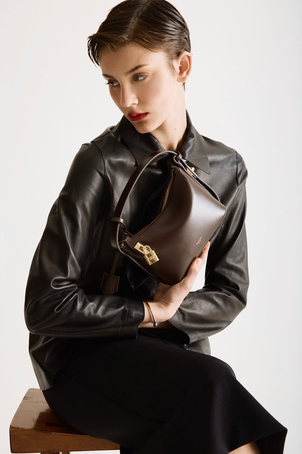 A person holding a Mini Gold Chocolate Hobo Shoulder Handbag