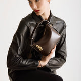 A person holding a Mini Gold Chocolate Hobo Shoulder Handbag