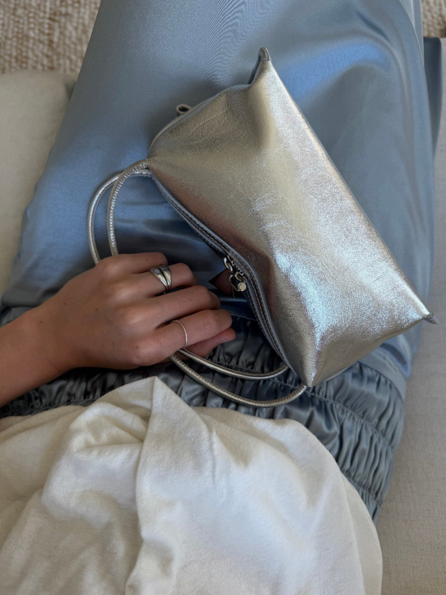 Person holding a silver handbag with a neutral background