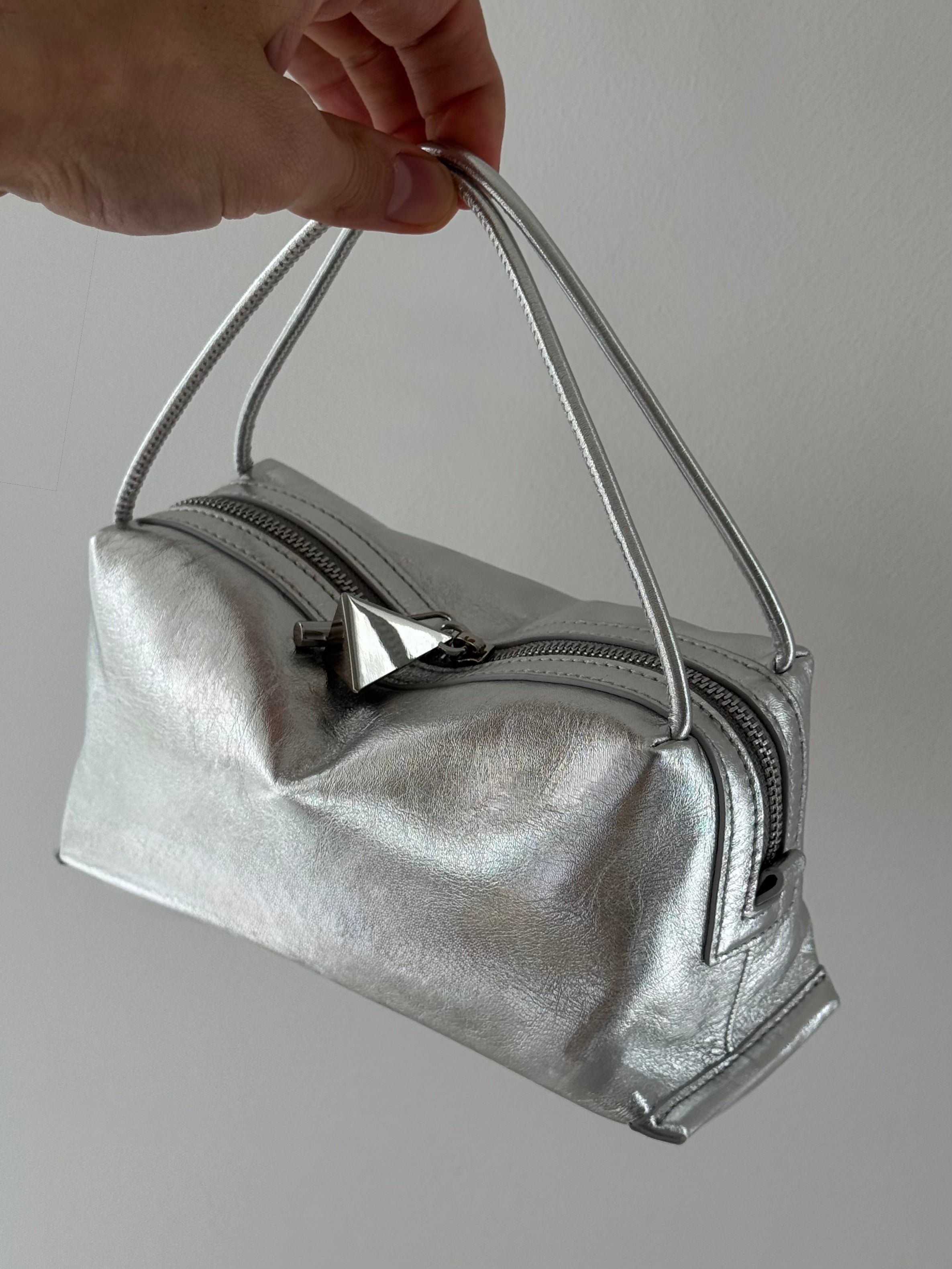 Silver Metallic Café Mini Crossbody Handbag held by a hand against a plain background