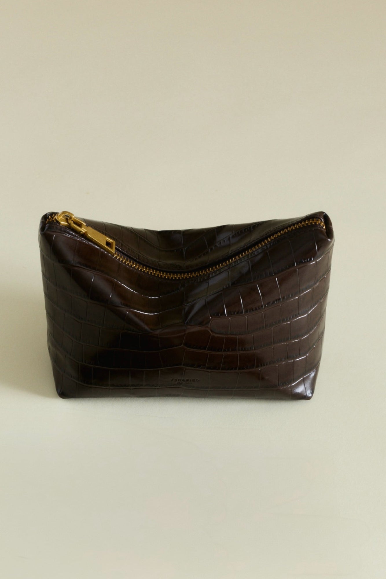 Mocha Croc Makeup Pouch with gold zipper on a beige background
