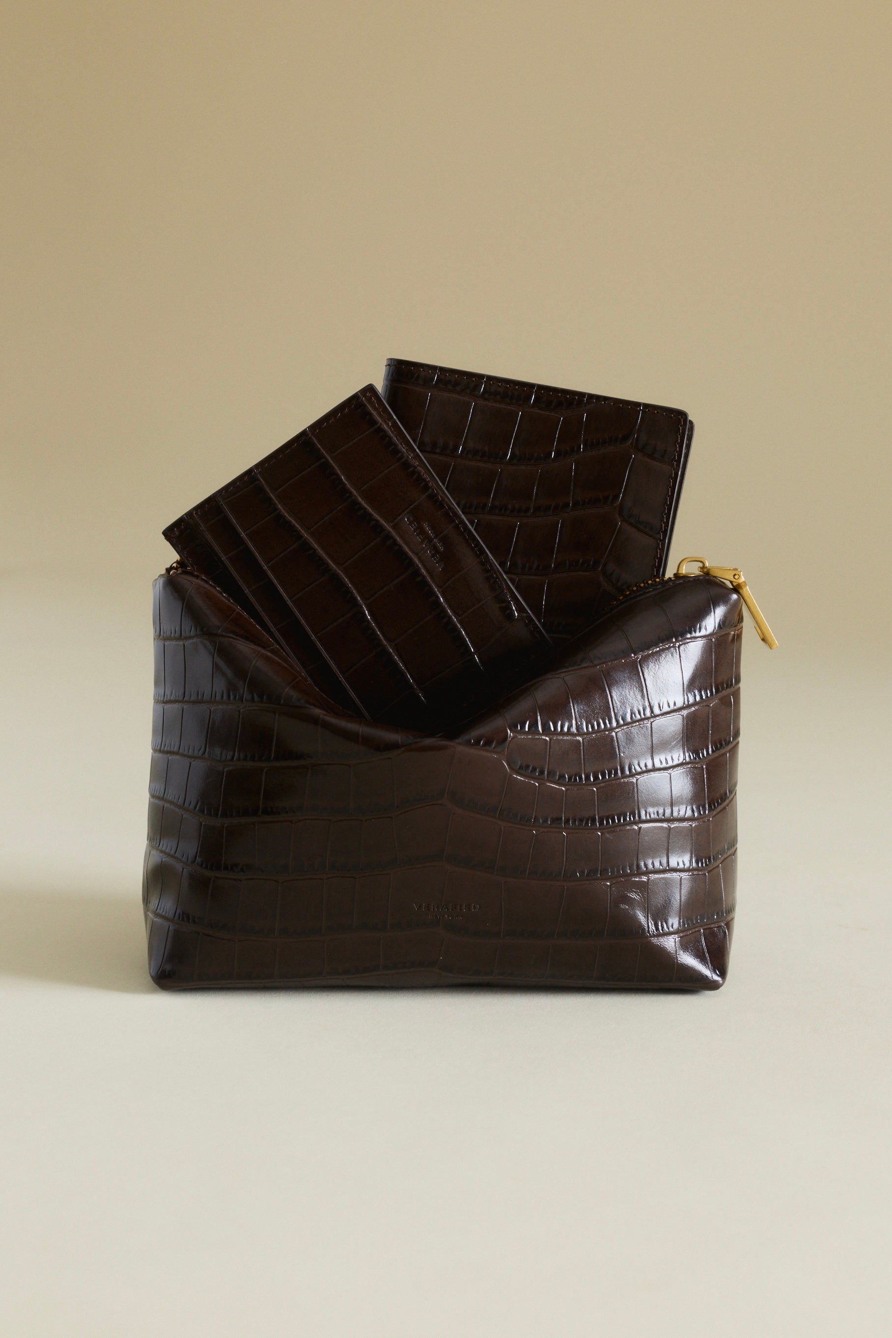 Brown crocodile-patterned clutch bag with a smaller Mocha Croc Embossed Passport Cover Wallet on a beige background