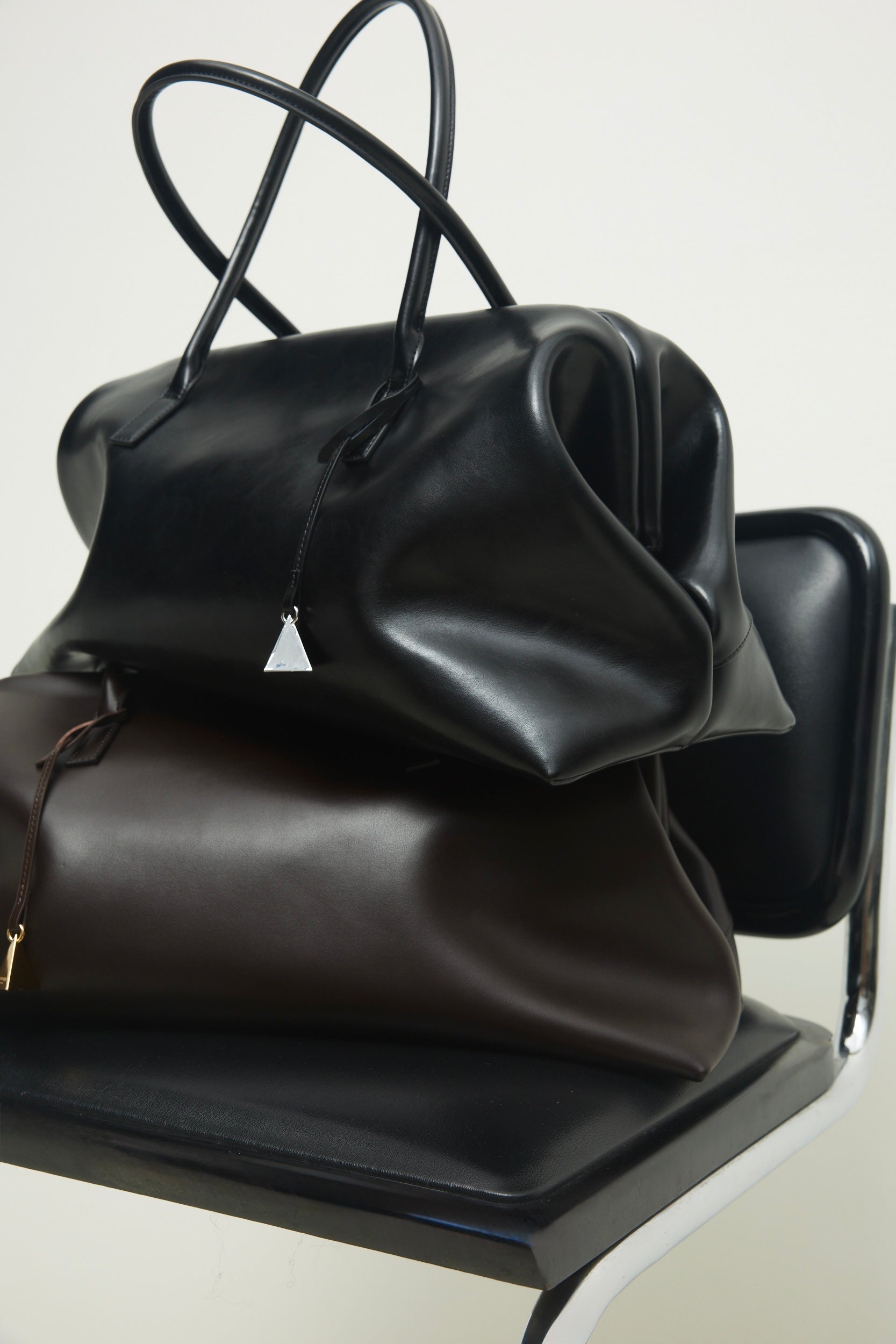 Three  Black Club Large Handbags on a chair with a white background