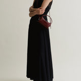 Person wearing a black dress holding a Maroon Python Café Mini Bag: Crossbody Handbag on a plain background