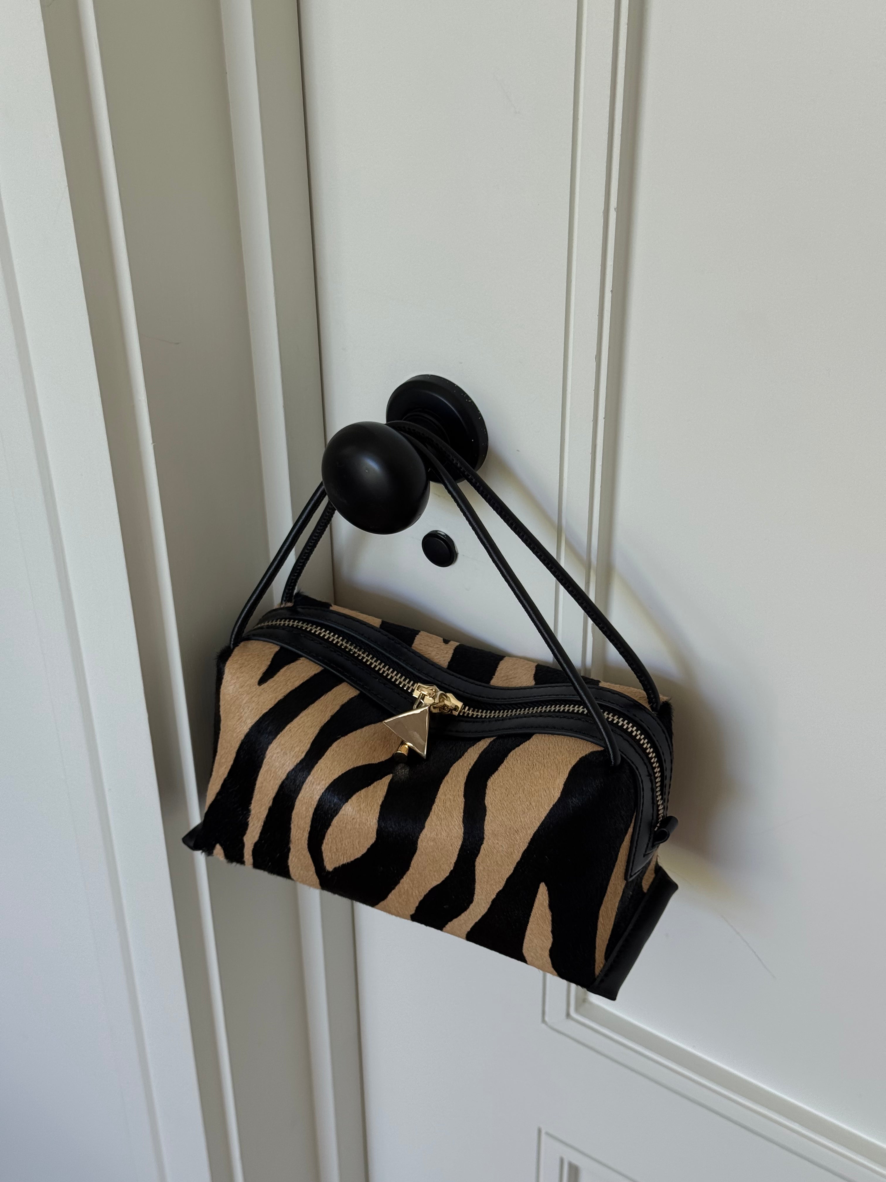 Zebra print handbag with black handles on a white door